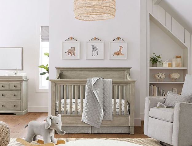 Hanging wall animal prints above wooded crib with small elephant rocker below.