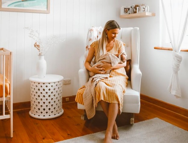 White glider in nursery with mother holding baby