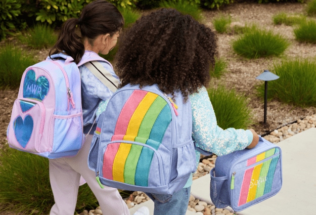 Two girls walk to school with their Pottery Barn Kids backpacks and lunch boxes in tow.