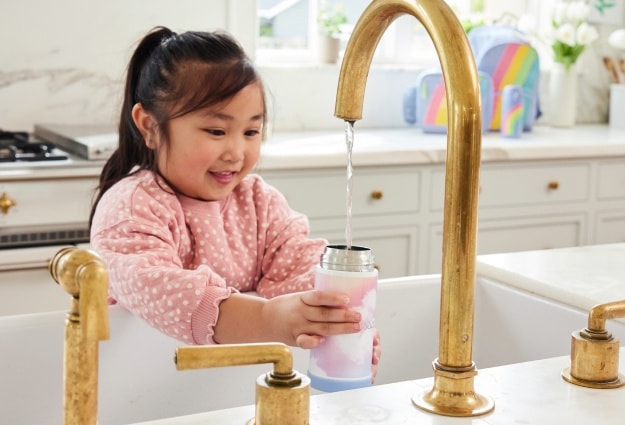 A young girl stands at the sink, filling her Pottery Barn Kids stainless-steel water bottle before heading to school.