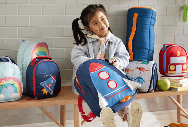 A girl is taking out a book from her Astor color-block backpack.