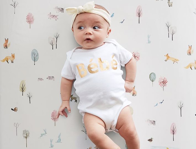 Baby wearing onesie on dakota woodland crib sheets.