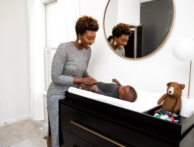 Round gold mirror over changing table