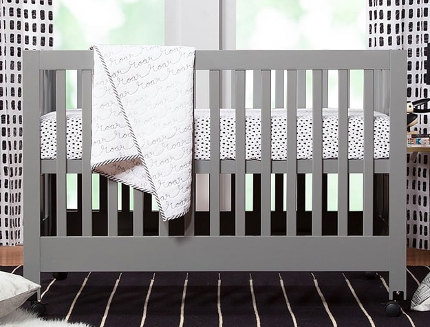 Gray folding crib in navy and white bedroom